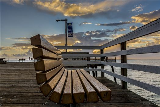 Rain slicked bench on Pismo Beach pier at sunset