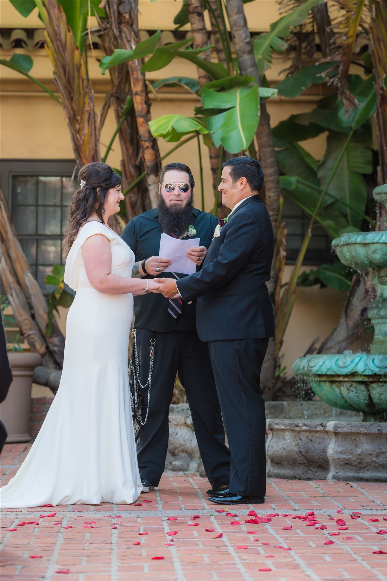 Mary and Alejandro 29 - Wedding photography at the Historic Santa Maria Inn in Santa Maria, California by Mirror's Edge Photography. Bride and Groom exchange rings in courtyard by Sarah Williams