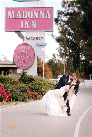 Mirror's Edge Photography captures Xochitl and David's magical Madonna Inn Wedding in San Luis Obispo, California. Bride and Groom dip kiss in front of Madonna Inn Sign.
