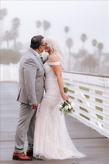 Rainy day wedding at the Shore Cliff Hotel Gazebo in Pismo Beach, California in San Luis Obispo County by Mirror's Edge Photography.  Misty and rainy Bride and Groom kissing on the boardwalk in Pismo Beach California.