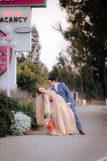 A gorgeous Madonna Inn Wedding by Mirror's Edge Photography a San Luis Obispo Wedding and Engagement Photographer.  Bride and Groom at sunset by Madonna Inn Sign.  70's theme wedding